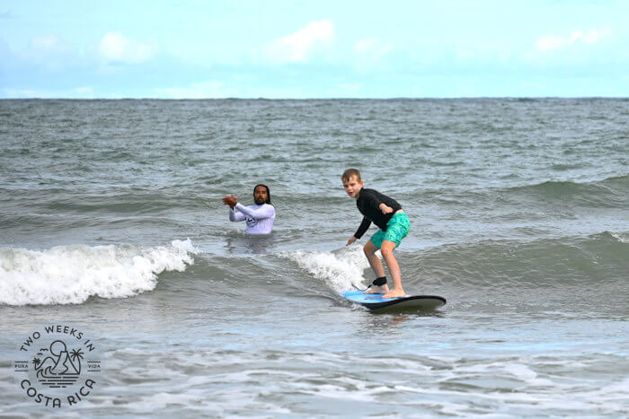 Kid surfing with instructor behind